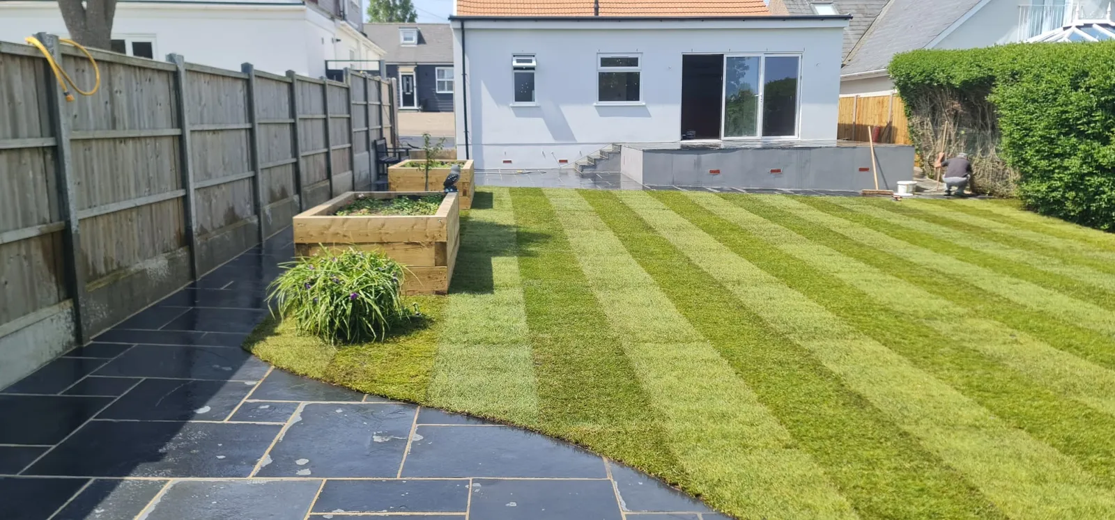 Striped lawn and raised timber planters in a finished rear garden