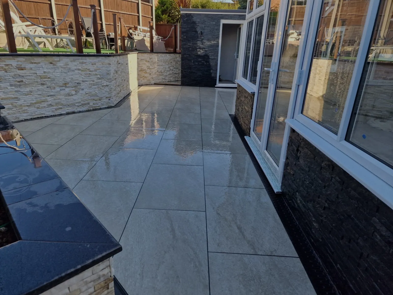 Porcelain patio with stone-clad raised beds and black granite edging
