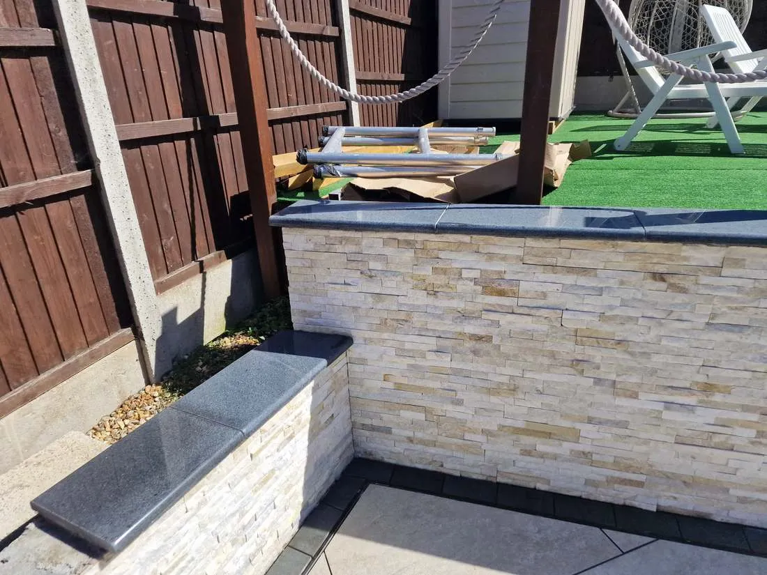 Stone-clad raised wall with granite coping by DJG Groundworks