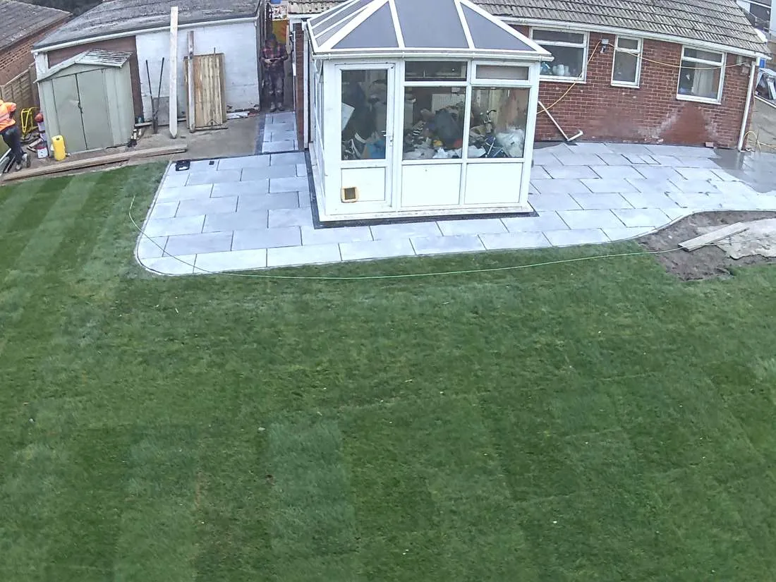 Curved porcelain patio around a conservatory with new turf by DJG Groundworks