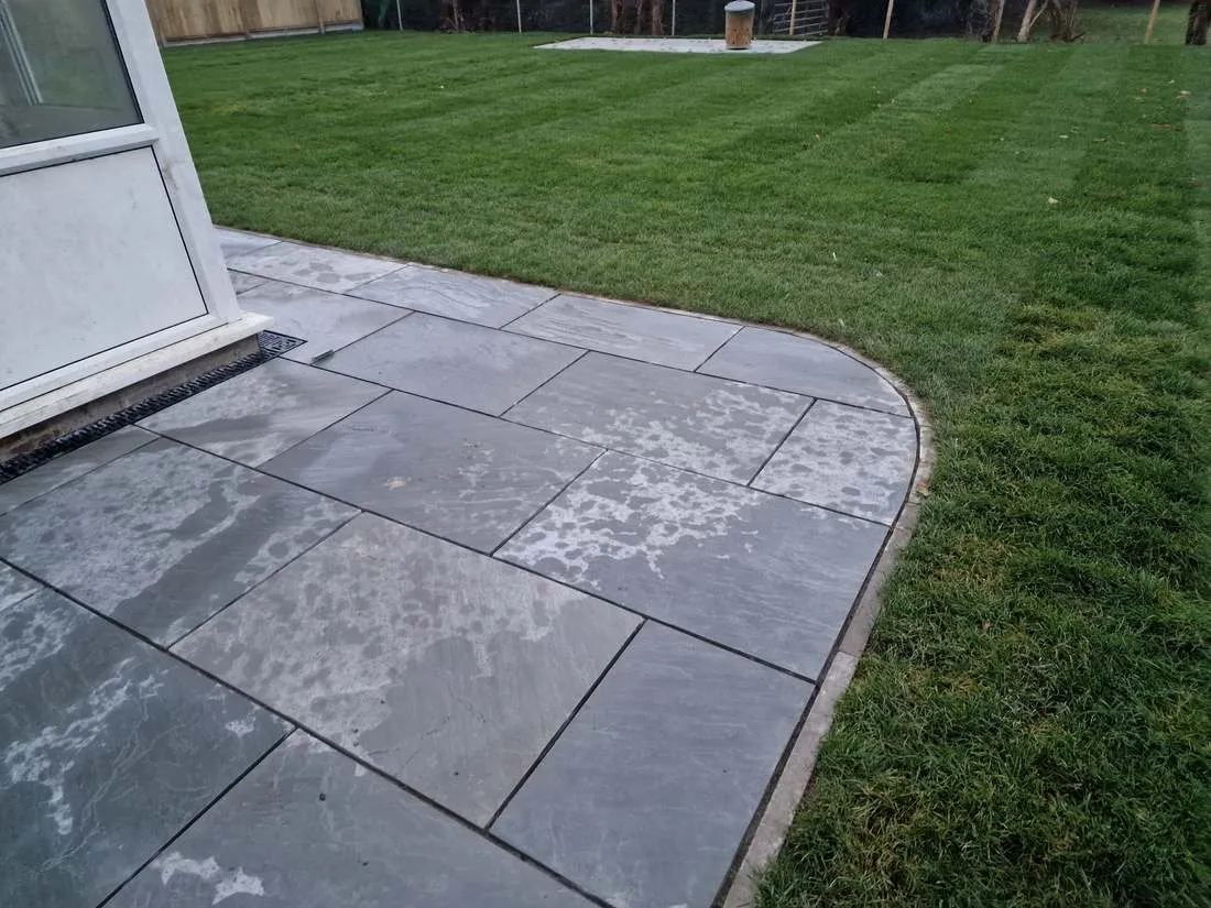 Striped new lawn meeting a curved patio by DJG Groundworks