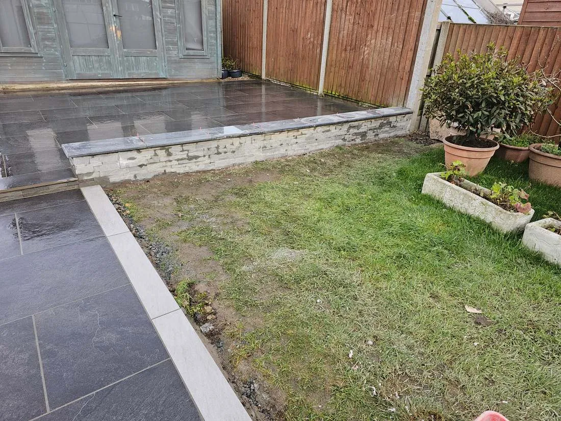 Slate-clad wall beside a porcelain patio by DJG Groundworks