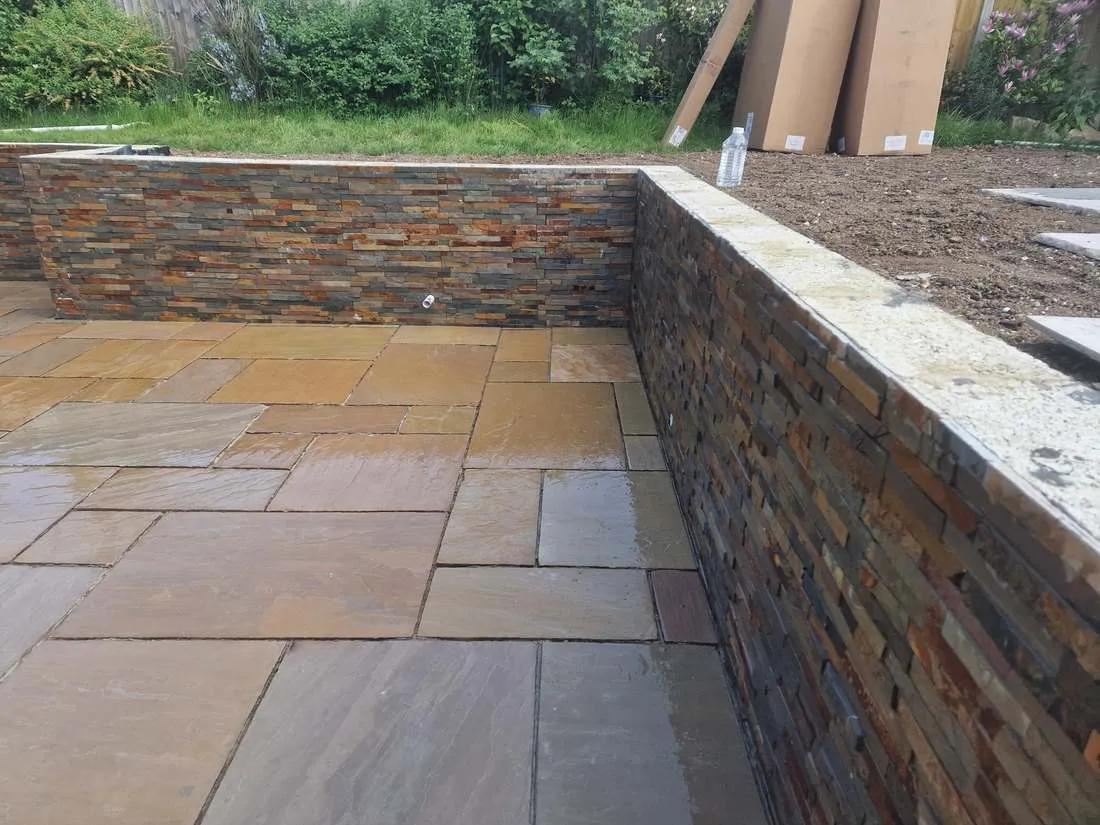 Slate-clad retaining walls around a patio by DJG Groundworks