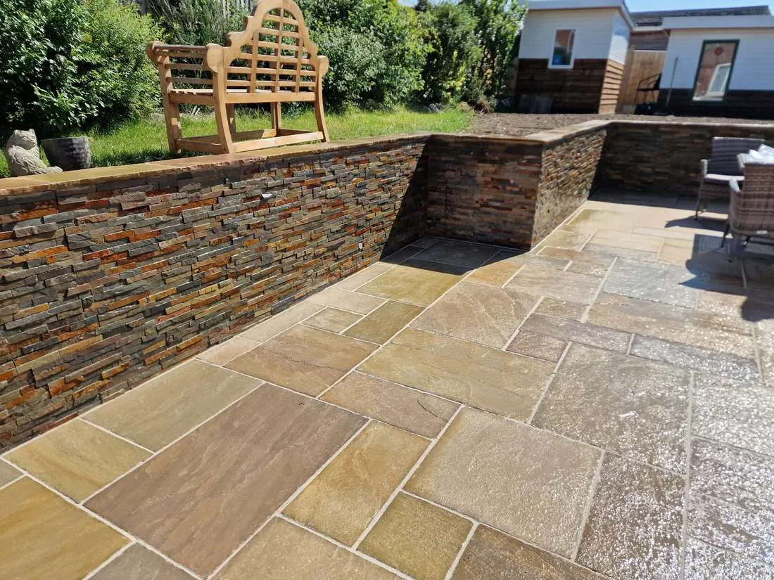 Sandstone patio with slate-clad retaining walls by DJG Groundworks