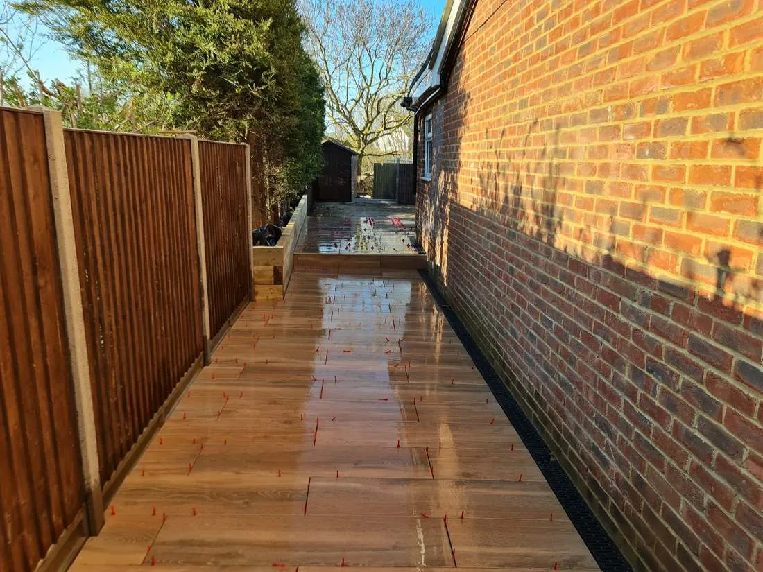 Wood-effect porcelain path beside a sleeper raised bed by DJG Groundworks
