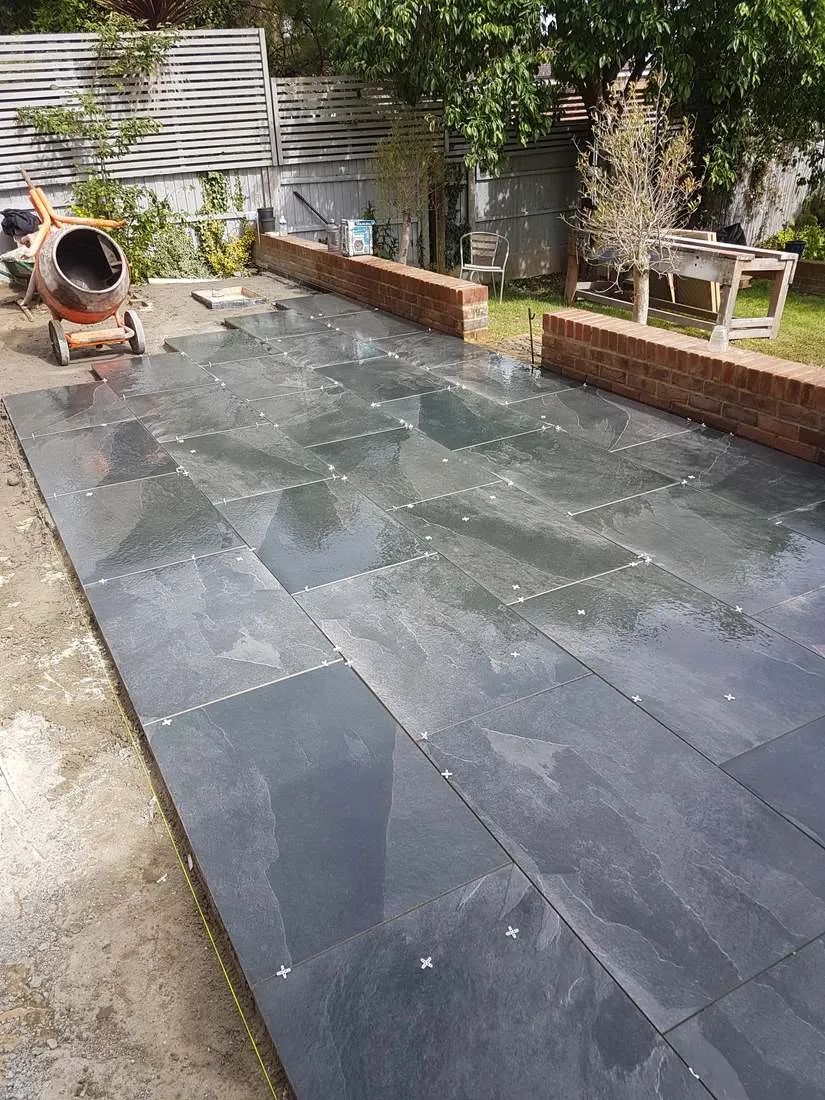 Black slate-effect patio with brick garden walls by DJG Groundworks