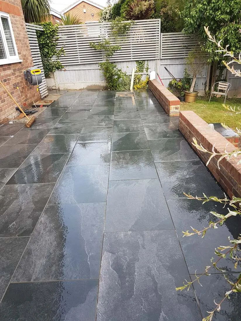 Slate-effect patio with brick planter walls by DJG Groundworks