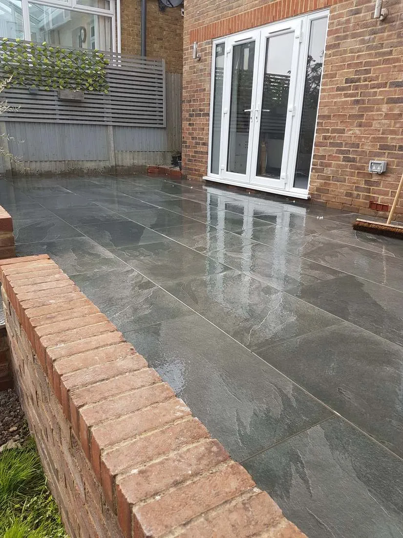 Slate-effect patio with brick wall and French doors by DJG Groundworks